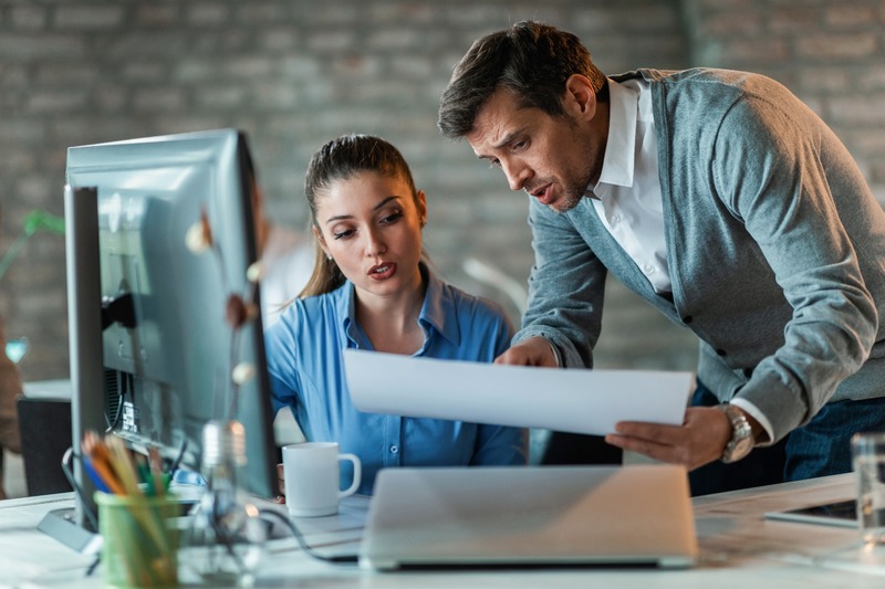 two-business-colleagues-talking-while-working-new-project-examining-blueprints-office